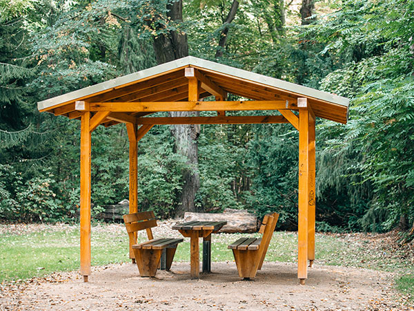 Gazebo in legno con panchine in un bosco